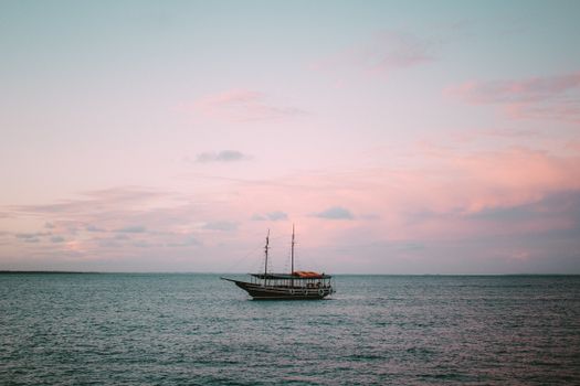 A serene view of a boat on the water during a vibrant sunset in Bahia, Brazil.