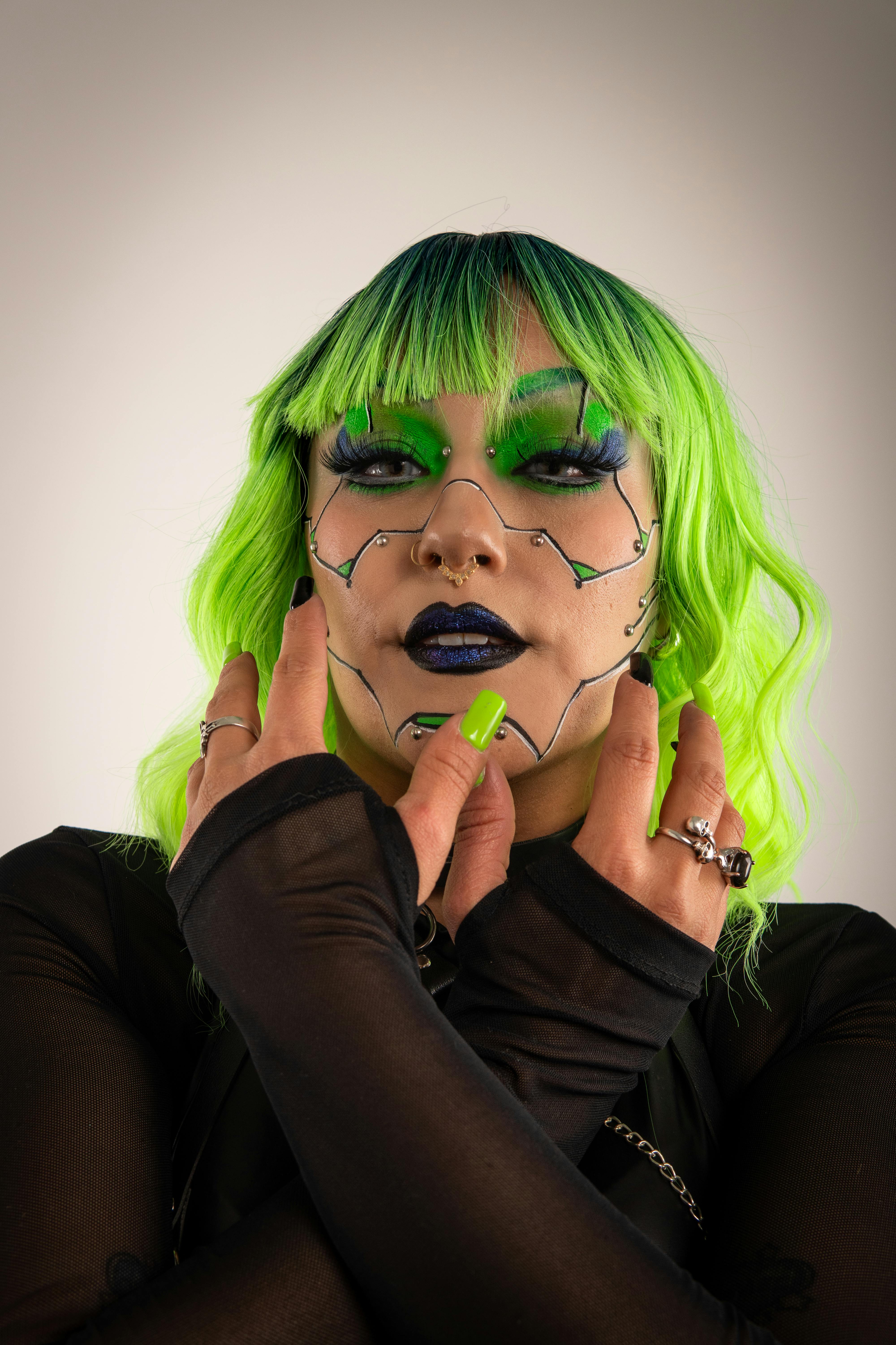Free Portrait of a person with bold cyberpunk makeup and bright green hair, showcasing unique fashion style. Stock Photo