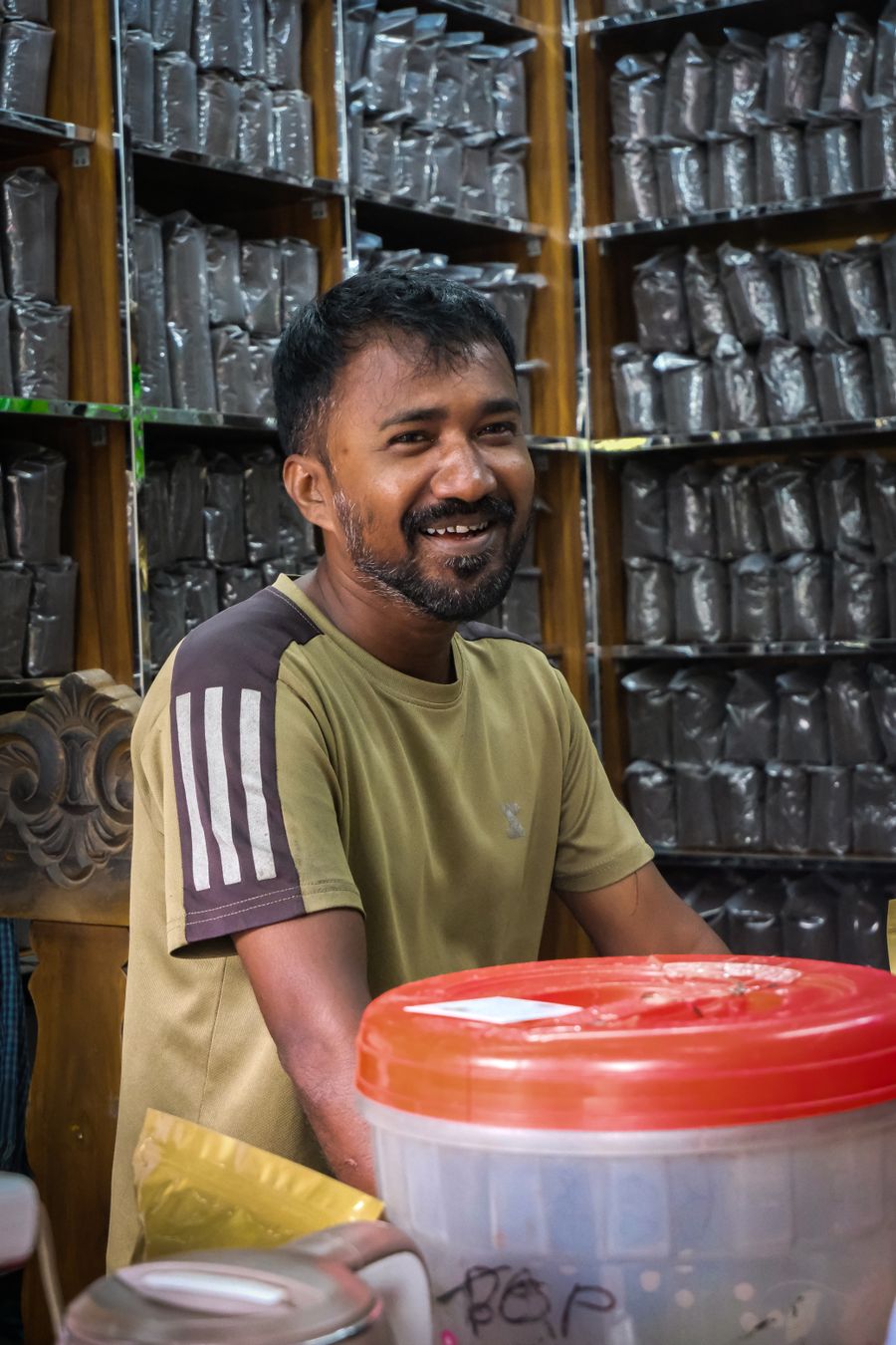 Friendly Indian shopkeeper smiling inside a tea store
