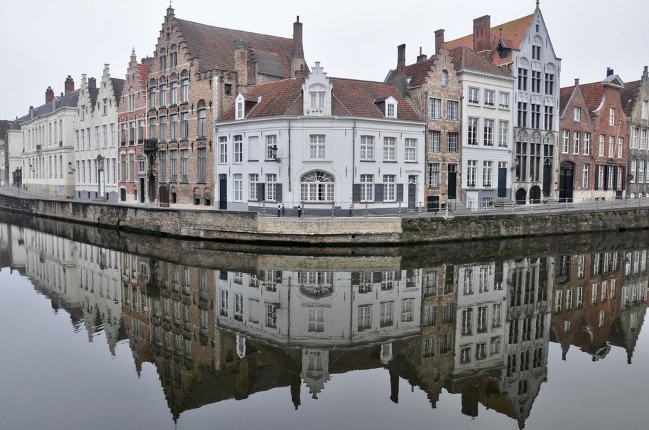 Picturesque canalside view of historic buildings reflecting in Bruges, Belgium.