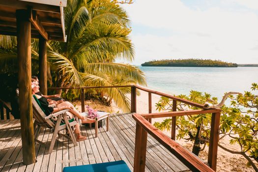 Une terrasse tropicale sereine surplombant une plage pittoresque, idéale pour la détente et l'ambiance des vacances.