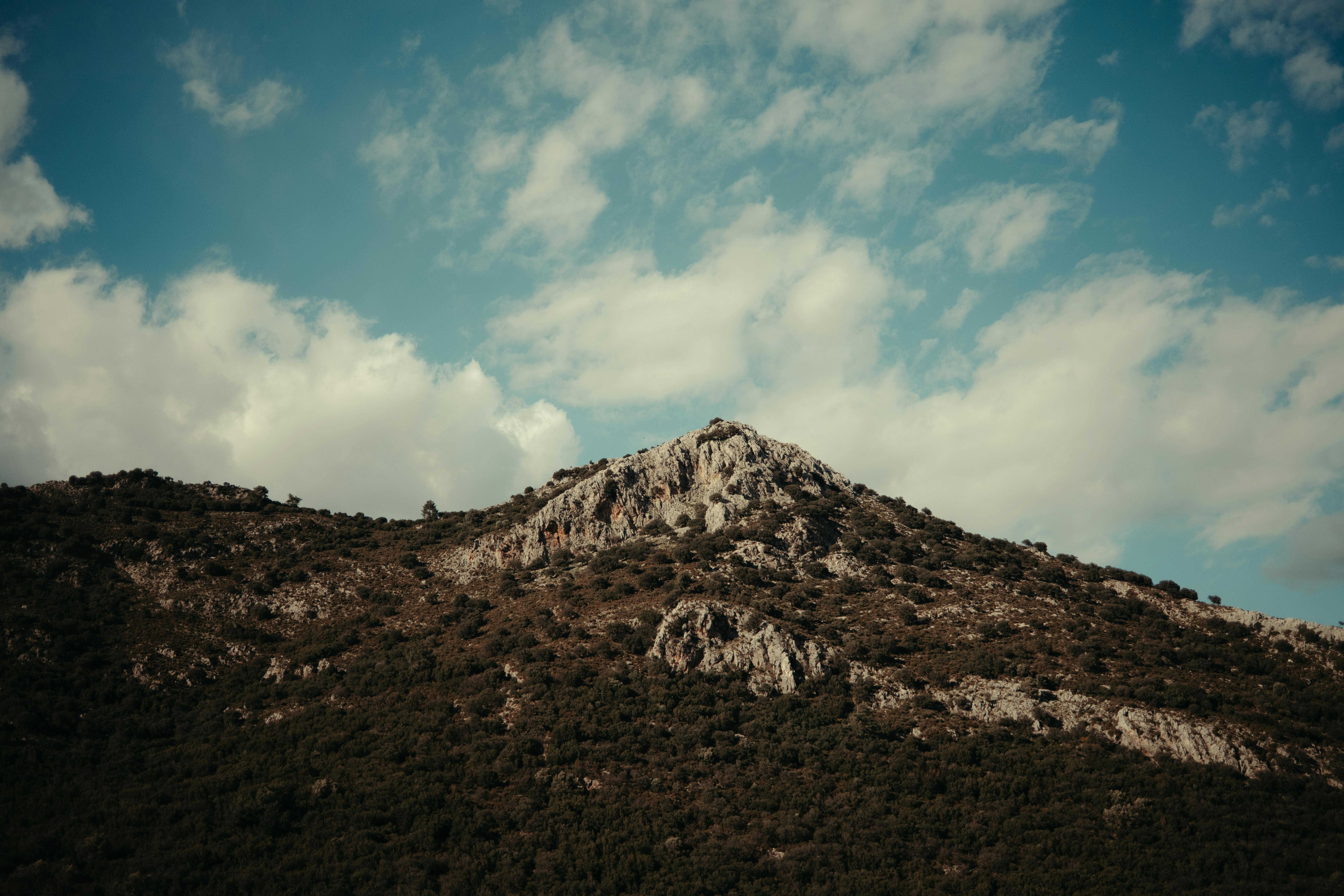 Free A stunning rocky mountain under a partially cloudy sky, offering a serene natural view. Stock Photo