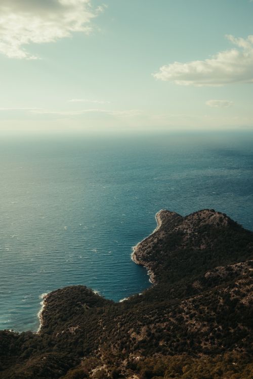Free Breathtaking aerial view of a coastal peninsula with lush greenery and serene blue sea. Stock Photo