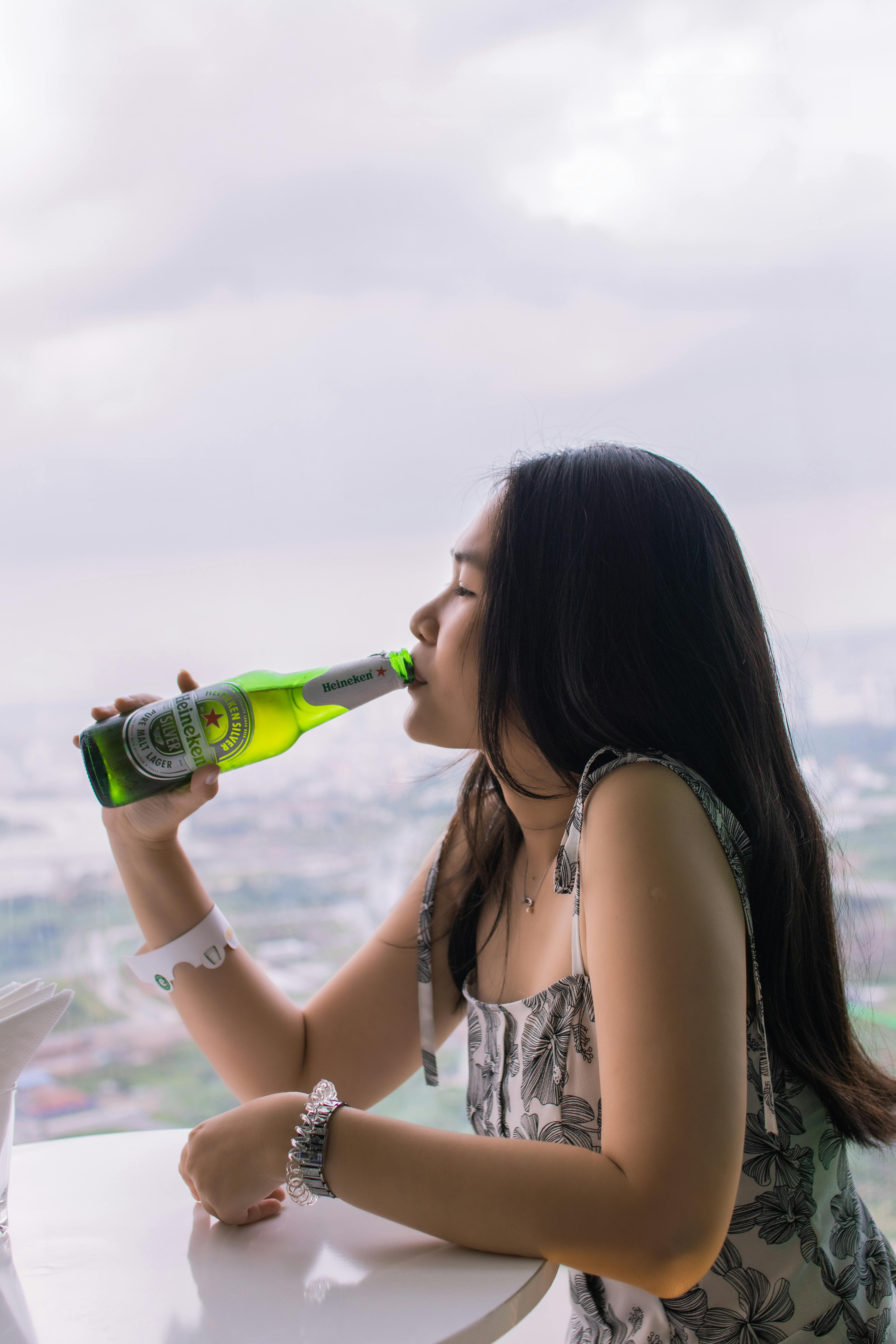 woman drinking green glass bottle