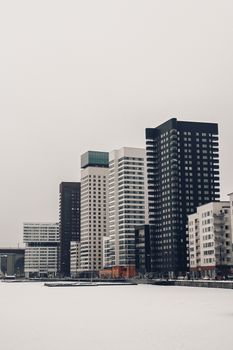 Cold urban skyline of Stockholm with modern skyscrapers along a frozen waterfront. Winter's minimal hues.