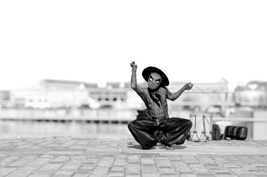 Black and white photo of a street performer in costume, creatively posing outdoors.
