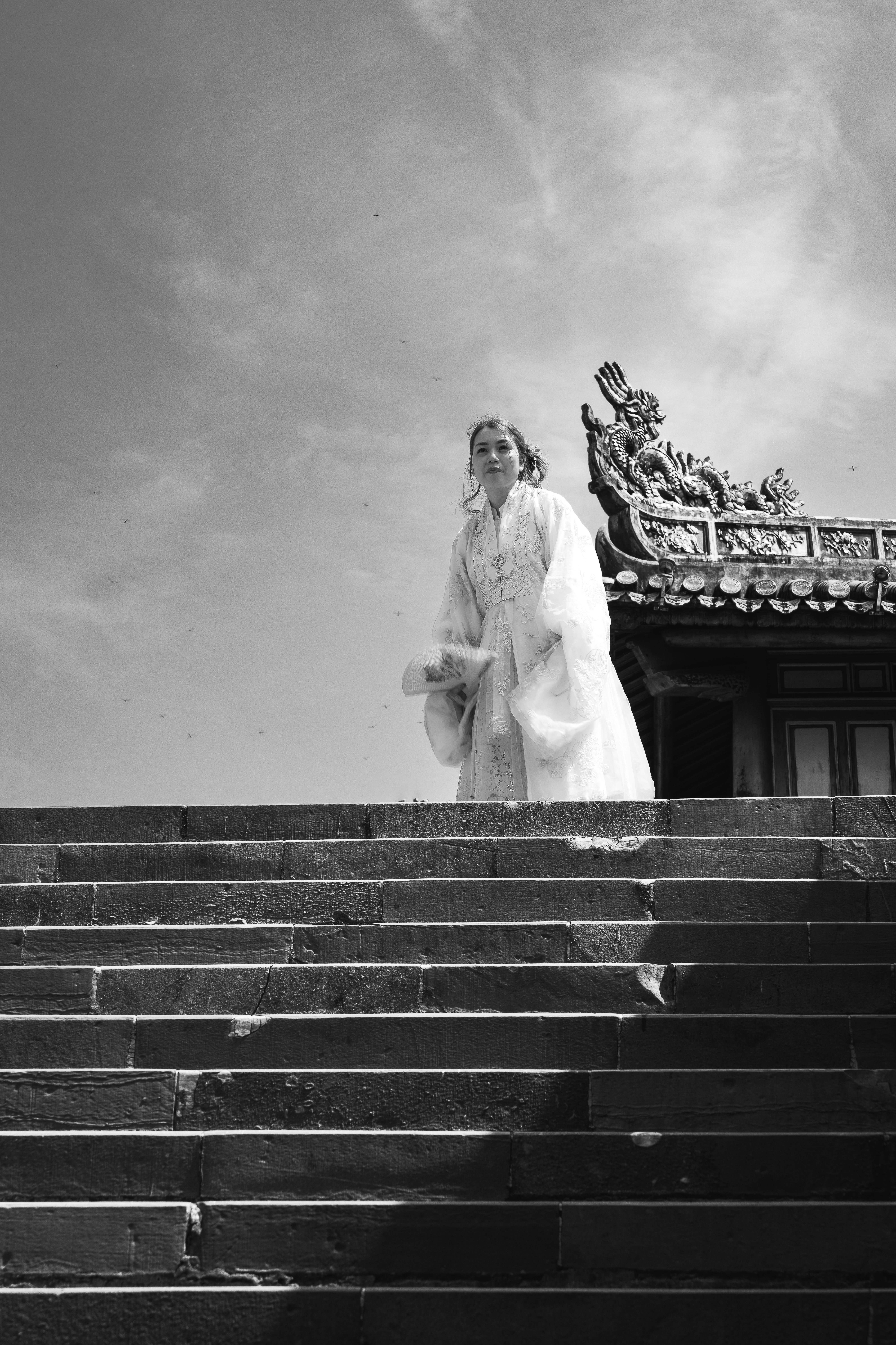 A person in traditional attire stands on the steps of Huế's Imperial Palace.