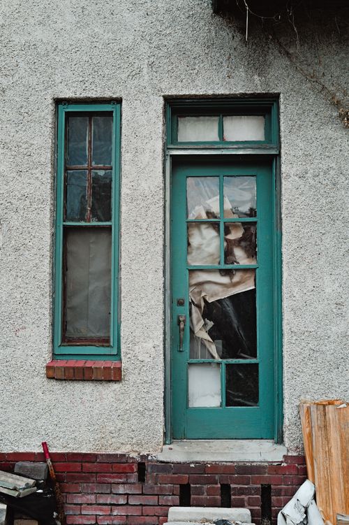Free A teal door and window on a textured wall, evoking a vintage charm and rustic setting. Stock Photo
