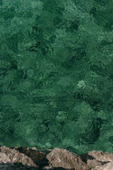 Aerial view of the vibrant green Mediterranean waters along the rocky coast of Budva, Montenegro.