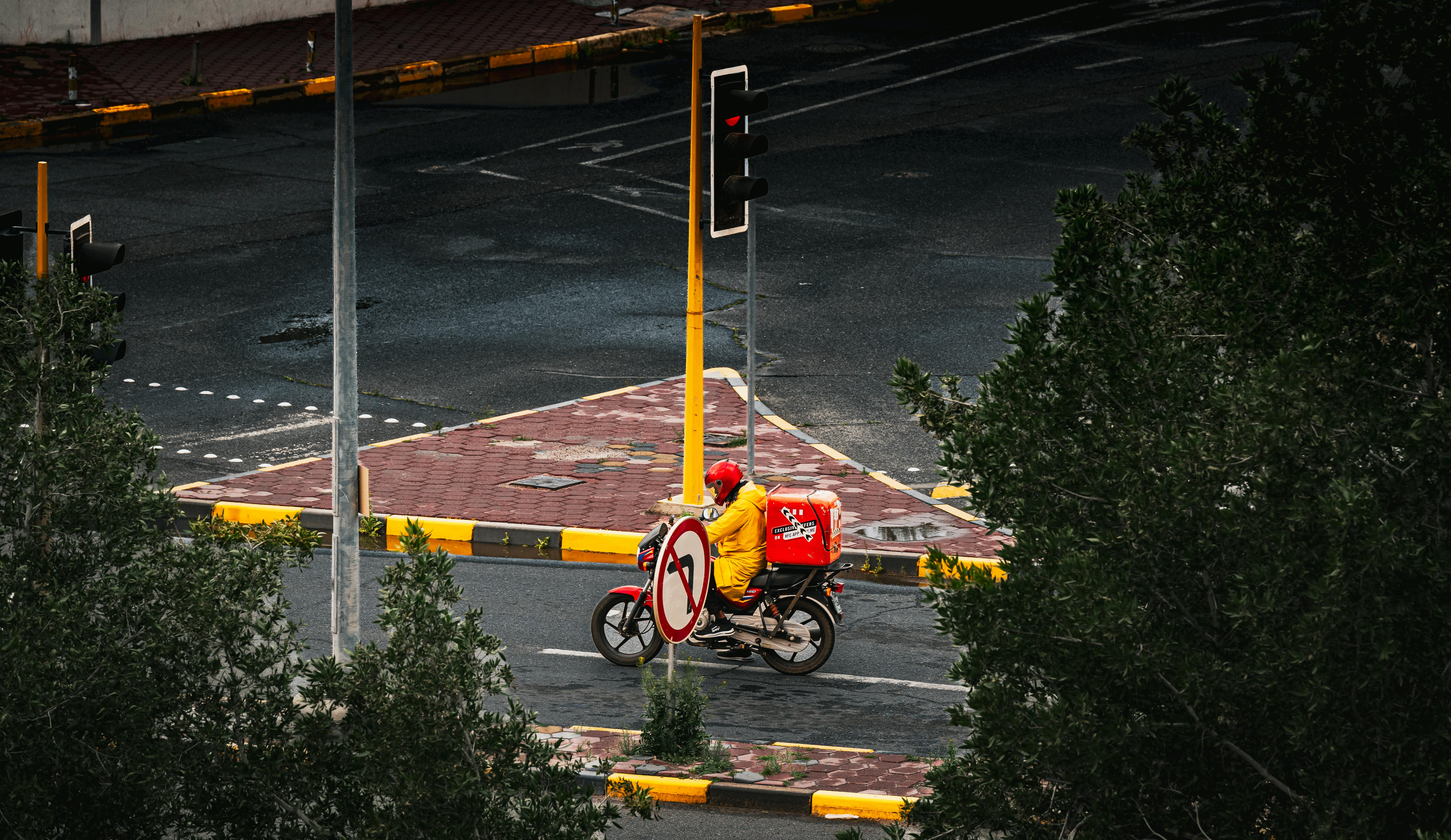 Free A delivery motorcyclist at a traffic-light intersection in Kuwait City, captured during the day. Stock Photo