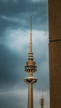 A striking view of the Kuwait Liberation Tower with a dramatic cloudy sky background.