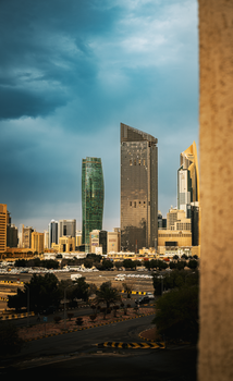 A vibrant skyline of Kuwait City showcasing modern skyscrapers against a dramatic sky.