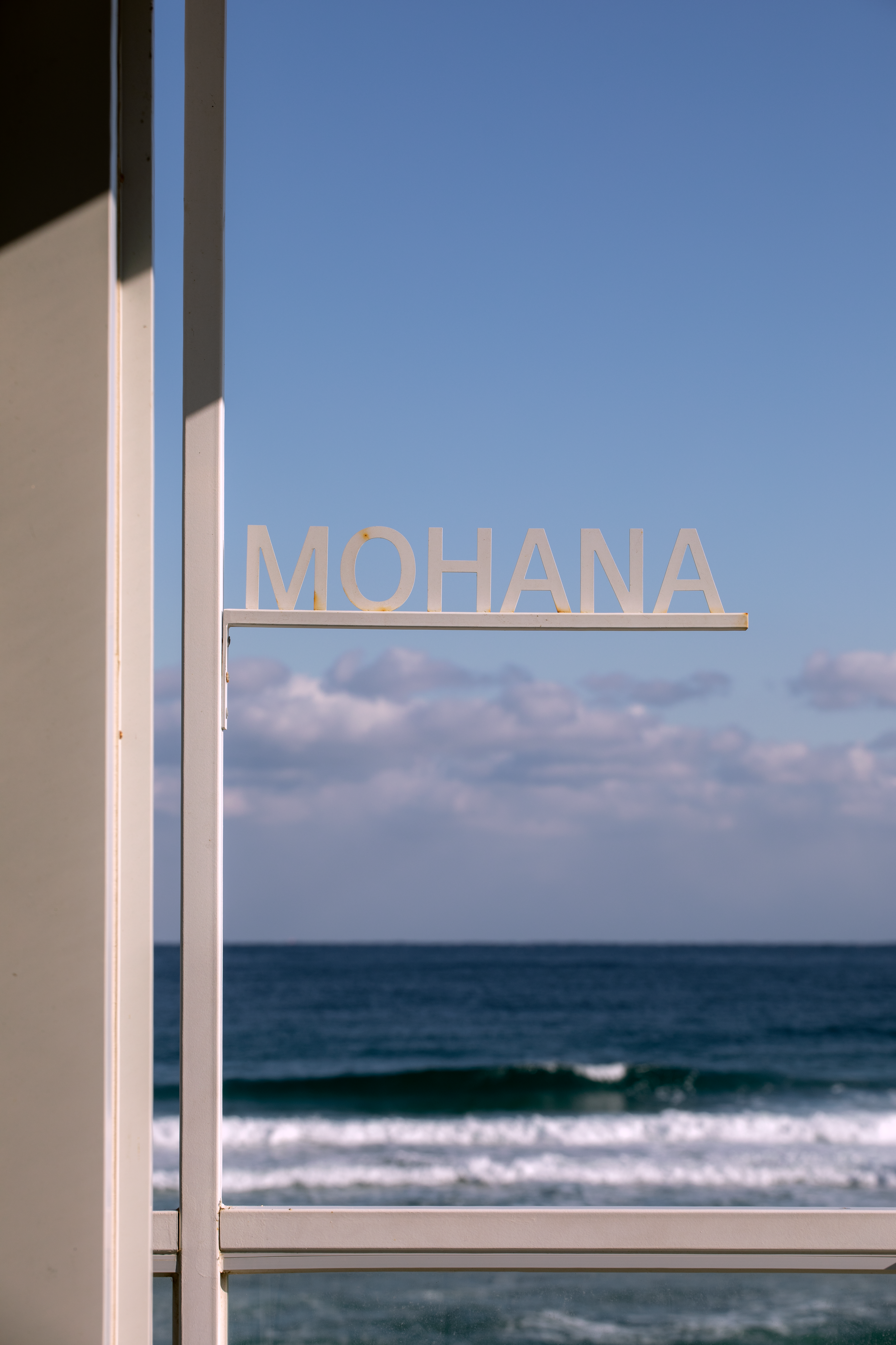 View of the ocean from a window with 'Mohana' sign, calm and peaceful.