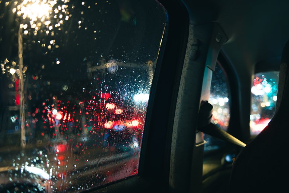 Rainy city lights seen through a wet car window, capturing urban nightlife ambiance.