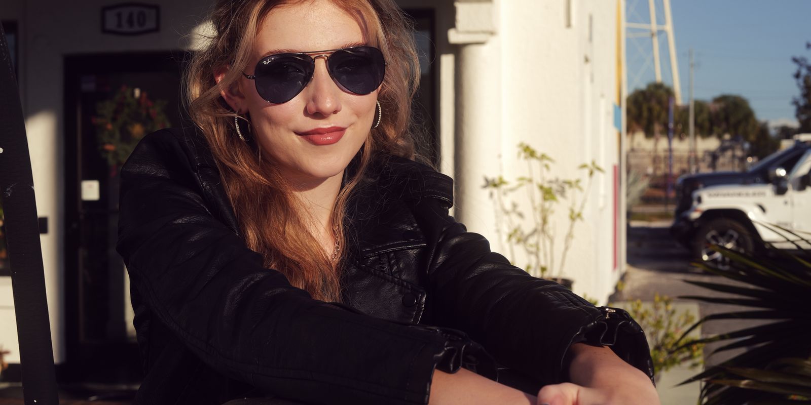 A stylish woman in sunglasses leans on a vintage gas pump at a retro-themed station - historic gas stations