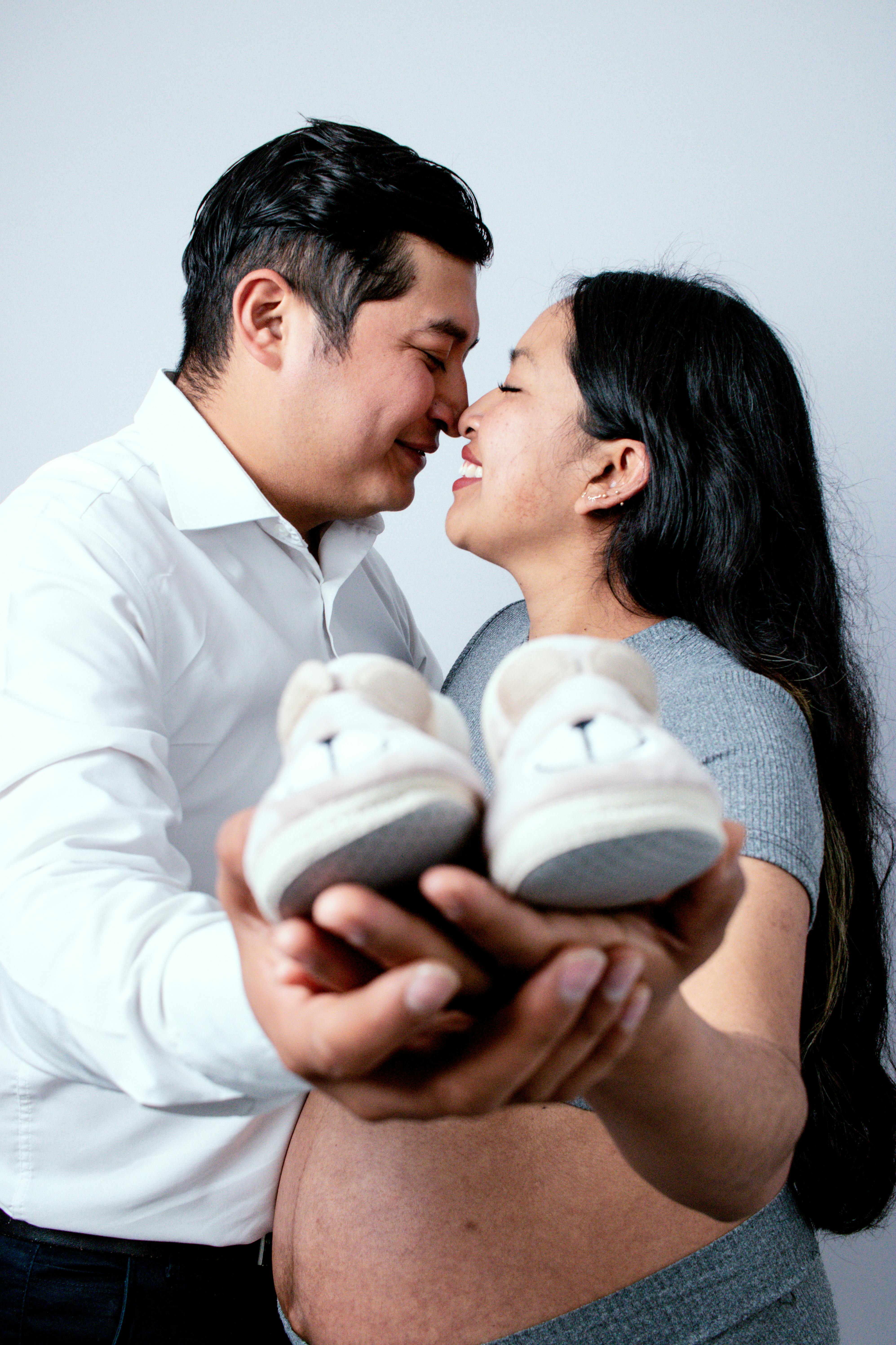 Expectant couple joyfully anticipating new baby, holding tiny shoes, symbolizes love, family, and future.