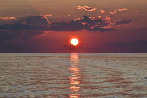 Free Breathtaking image of a vibrant sunset casting reflections on the tranquil ocean surface. Stock Photo