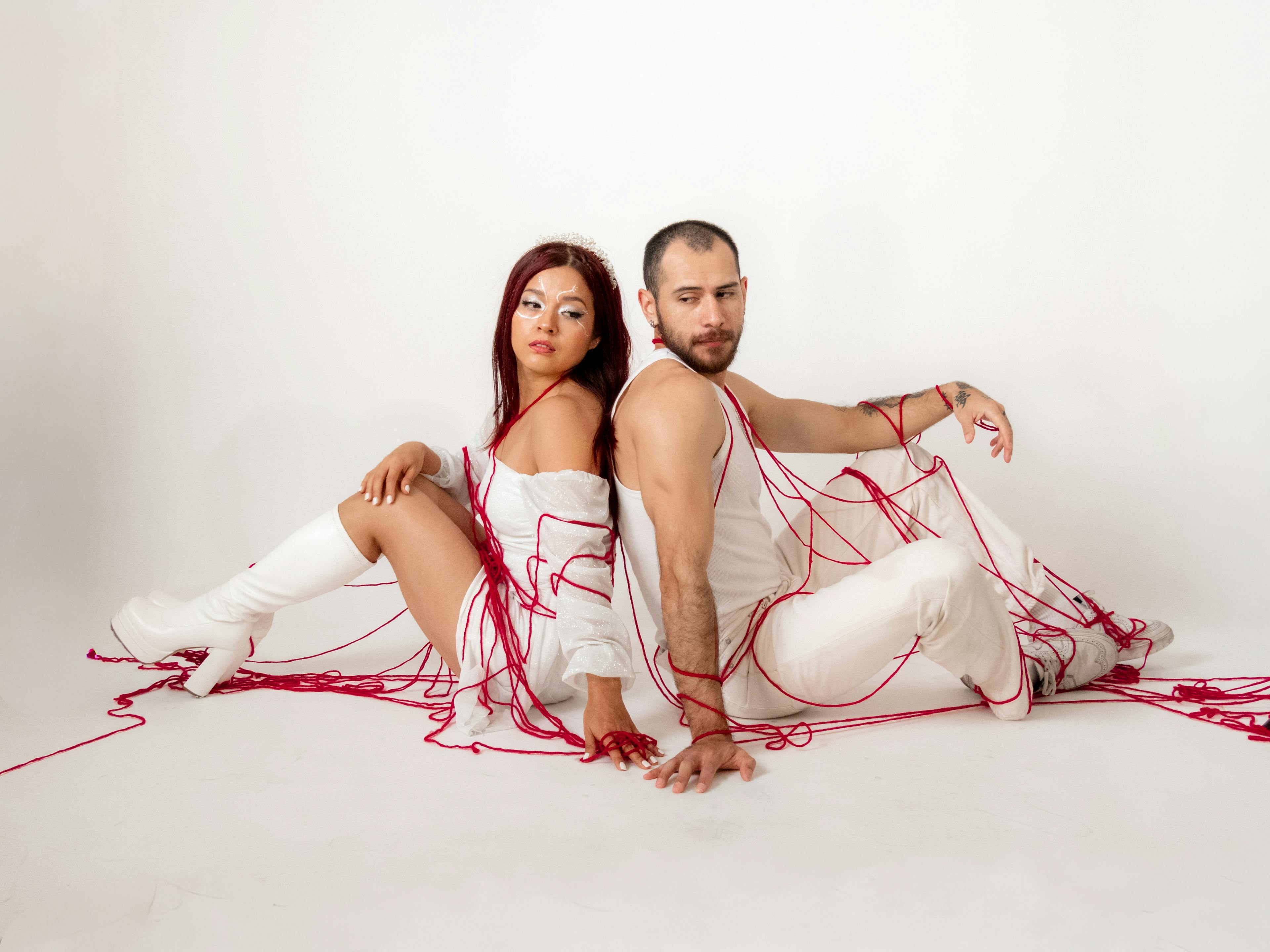 Artistic photo of a couple wrapped in red threads, conveying connection and emotion.