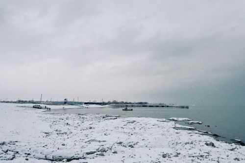 Free A serene winter landscape of a snowy shoreline with calm waters in Konaev, Kazakhstan. Stock Photo