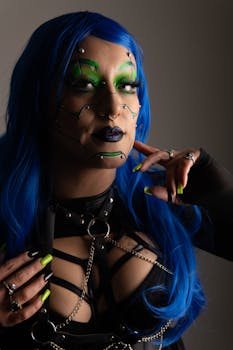 Portrait of a person in cyberpunk style with blue hair, green makeup, and black leather outfit.