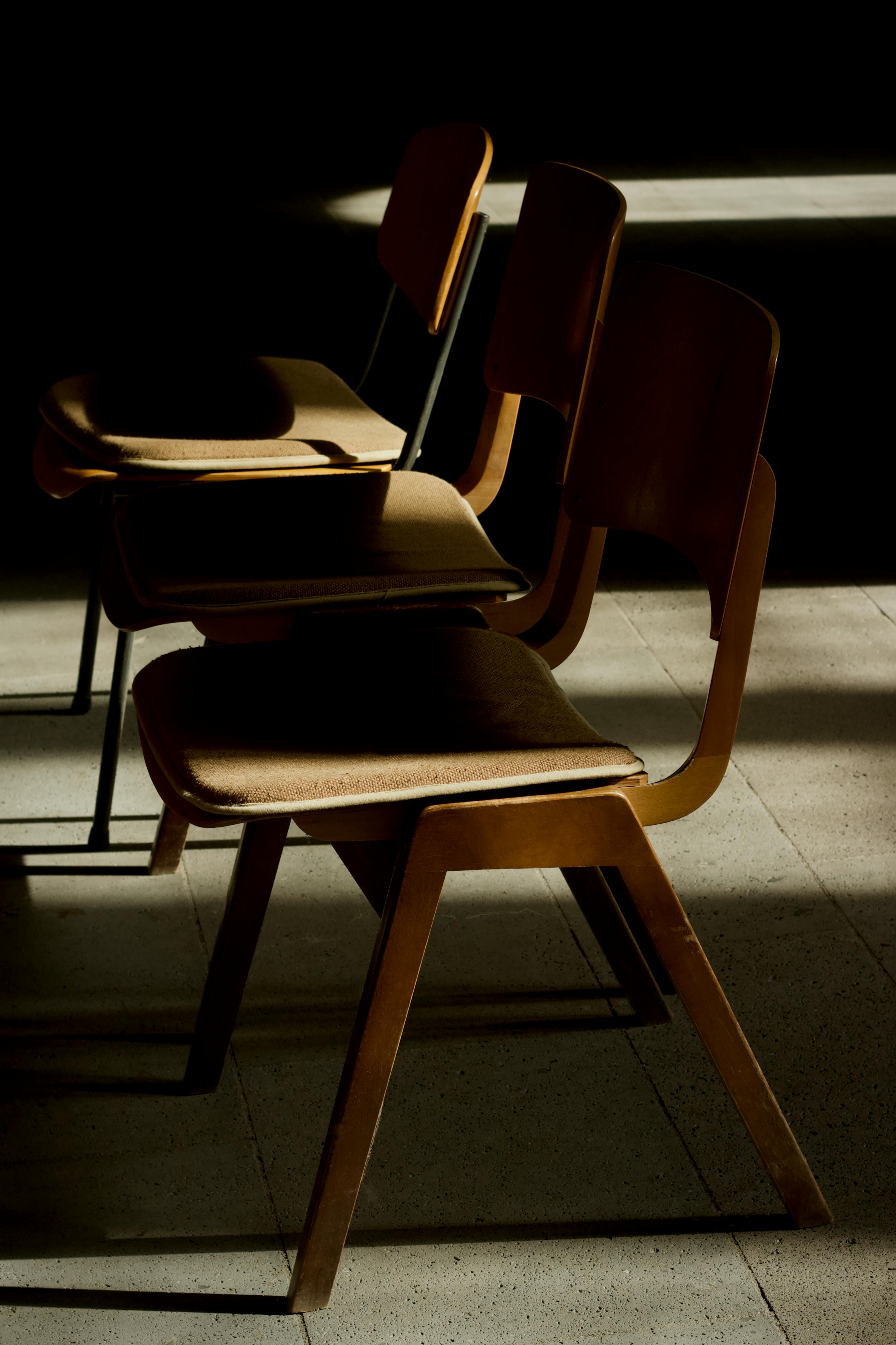 бесплатная Художественная фотография старинных деревянных стульев в эффектном солнечном свете, создающая классическую атмосферу. Стоковое фото