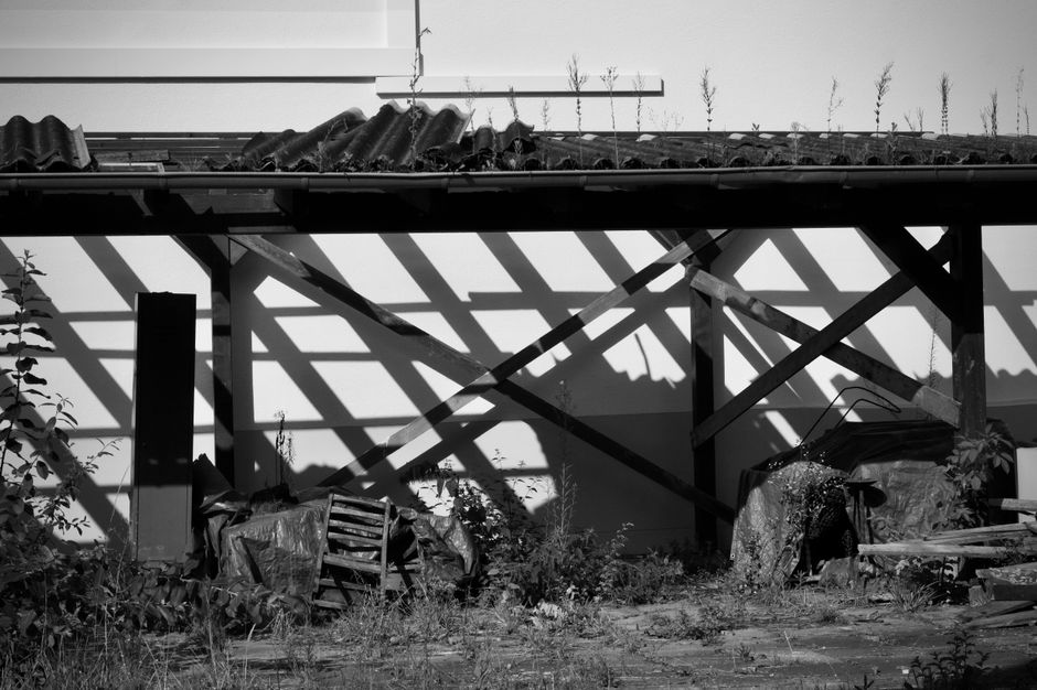 Monochrome image of shadows cast on an abandoned structure's wall.
