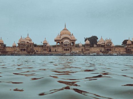 Serene view of ancient architectural temples reflecting in a tranquil river in India.