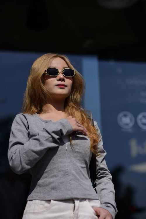 Free Stylish woman wearing sunglasses and casual attire enjoying a sunny day outdoors. Stock Photo