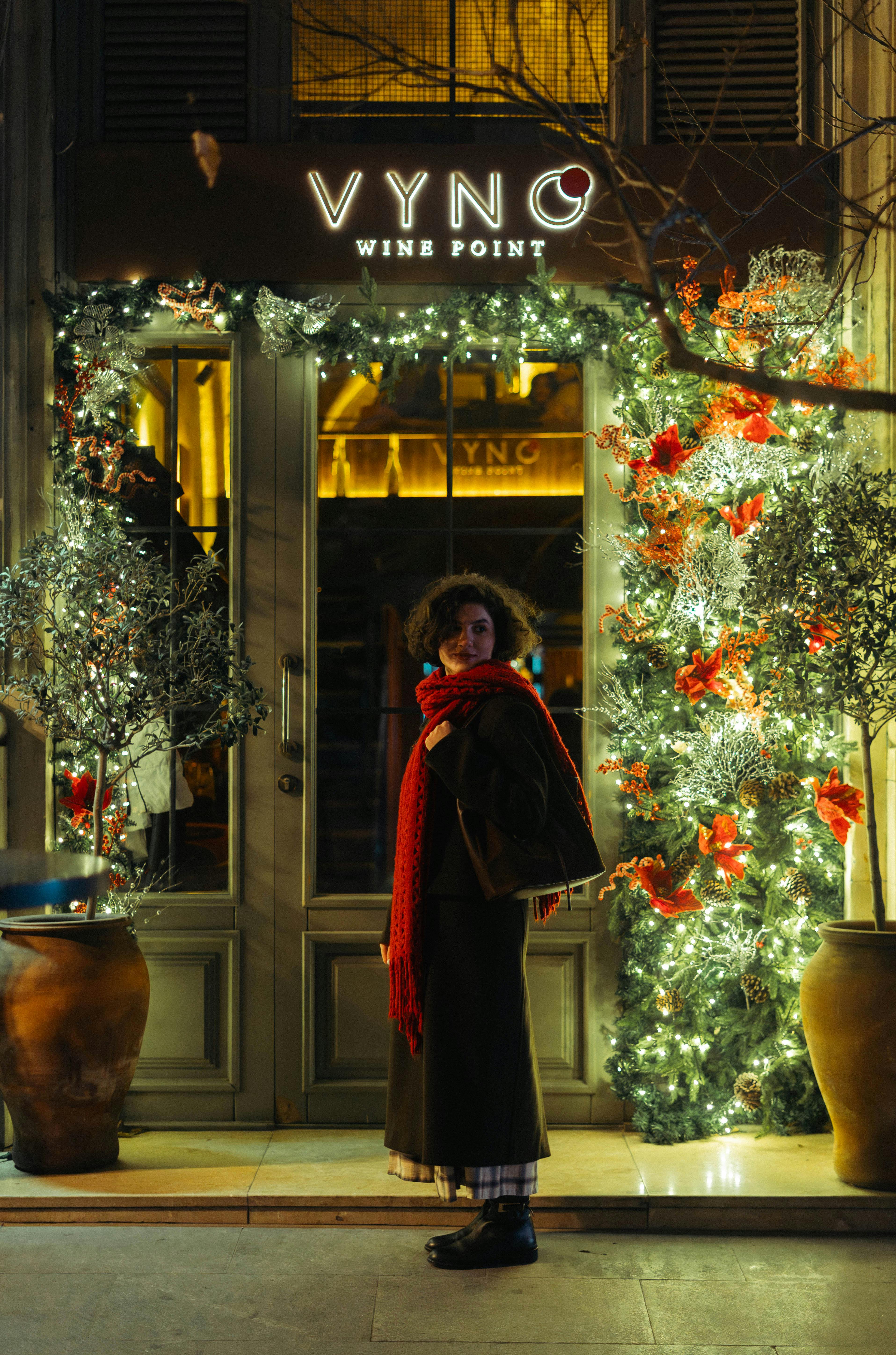 Woman in red scarf by festive doorway in Baku, Azerbaijan at night.