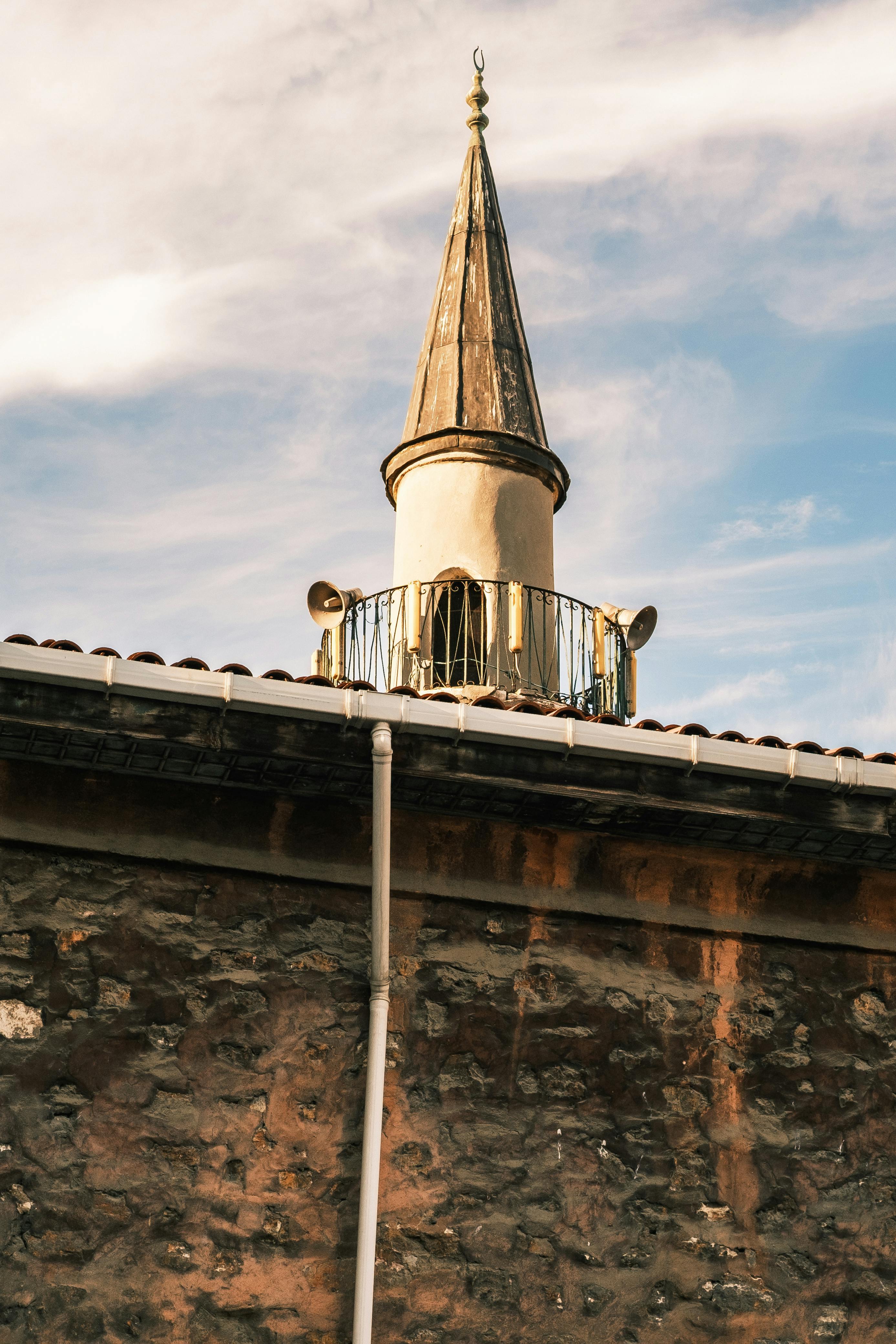 бесплатная Фотография очаровательного архитектурного шпиля на вершине простого каменного здания на фоне чистого неба. Стоковое фото