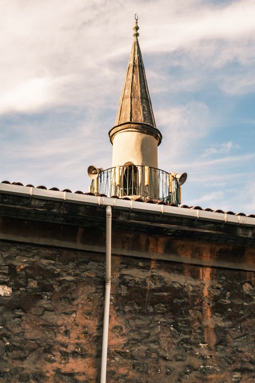 Free Photograph of a charming architectural spire atop a rustic stone building with a clear sky. Stock Photo