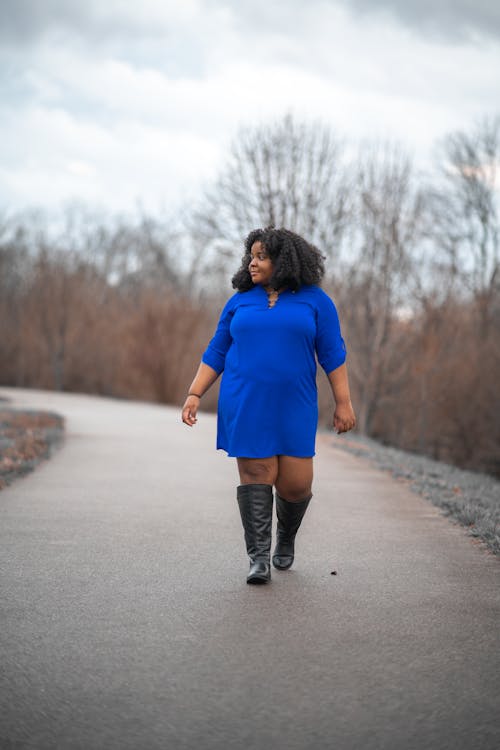 Femme En Robe Bleue Et Bottes Noires Marchant Seul Sur Une Route Vide