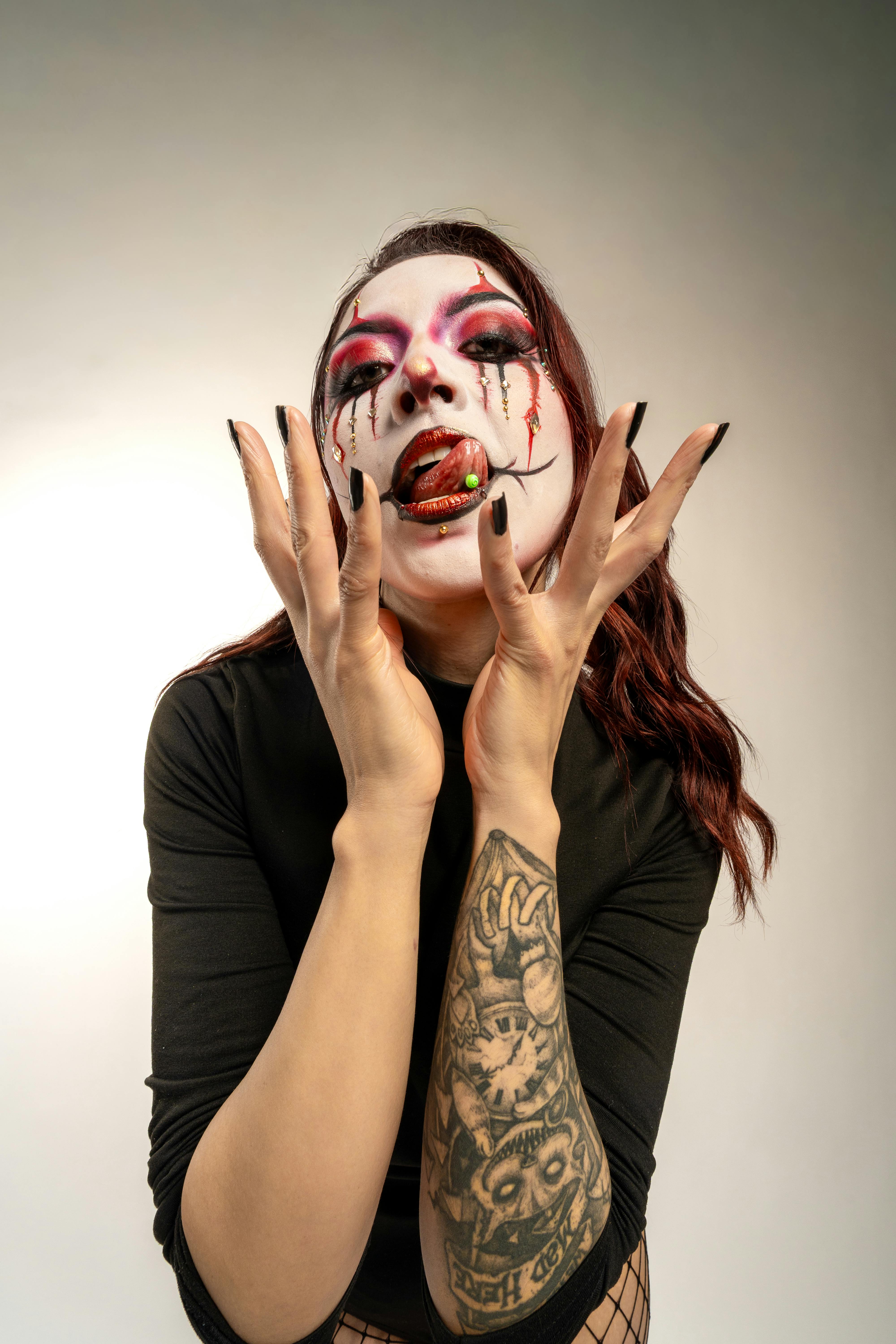 A vibrant portrait of a woman with striking carnival clown makeup and tattoos.