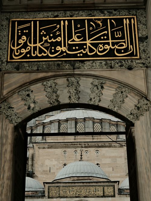 Free View of a mosque through an ornate archway with Arabic calligraphy. Elegant historical architecture. Stock Photo