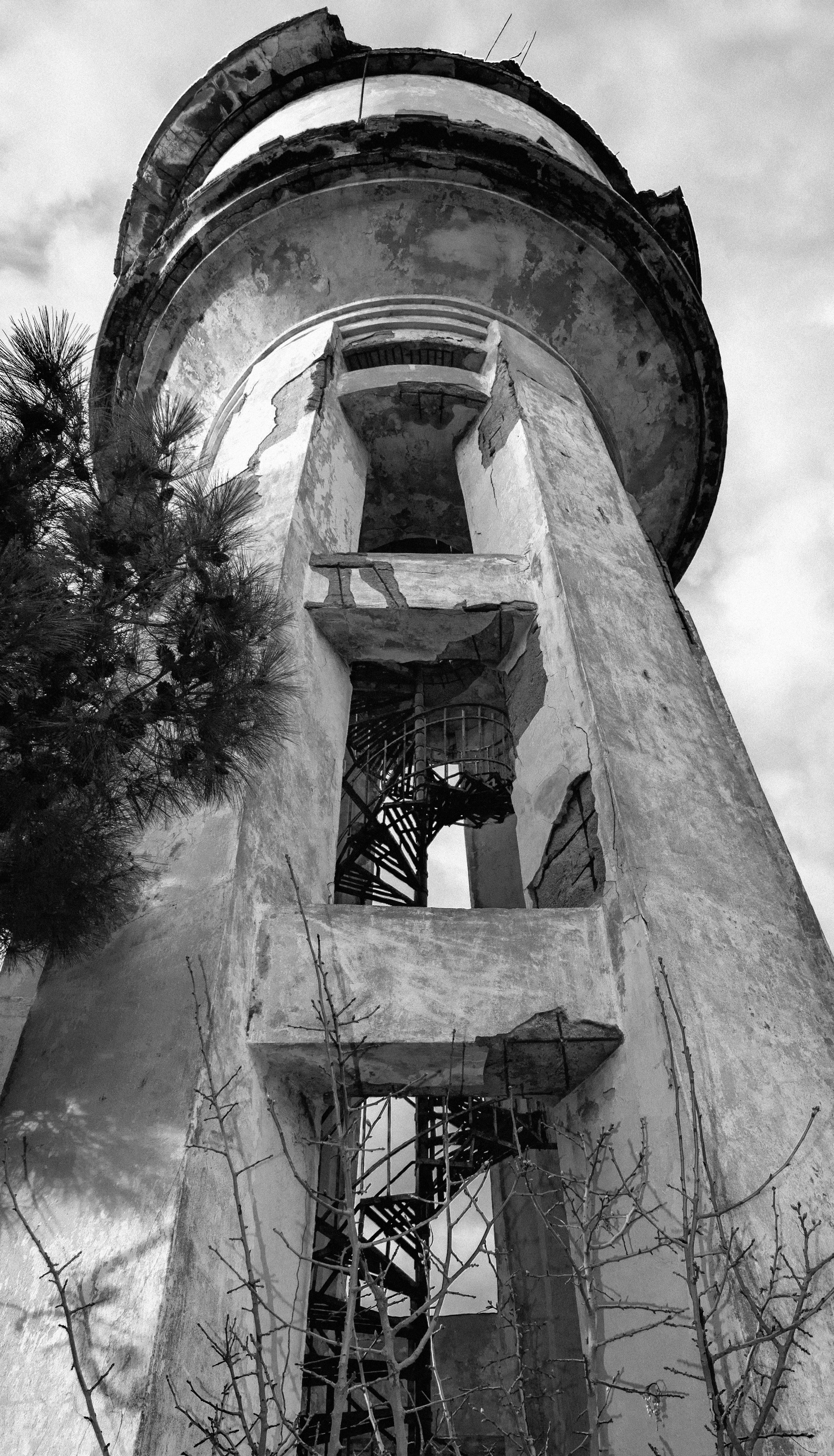 Gratis Pemandangan dramatis sebuah menara terbengkalai dengan tangga spiral, diabadikan dalam warna hitam putih. Foto Stok