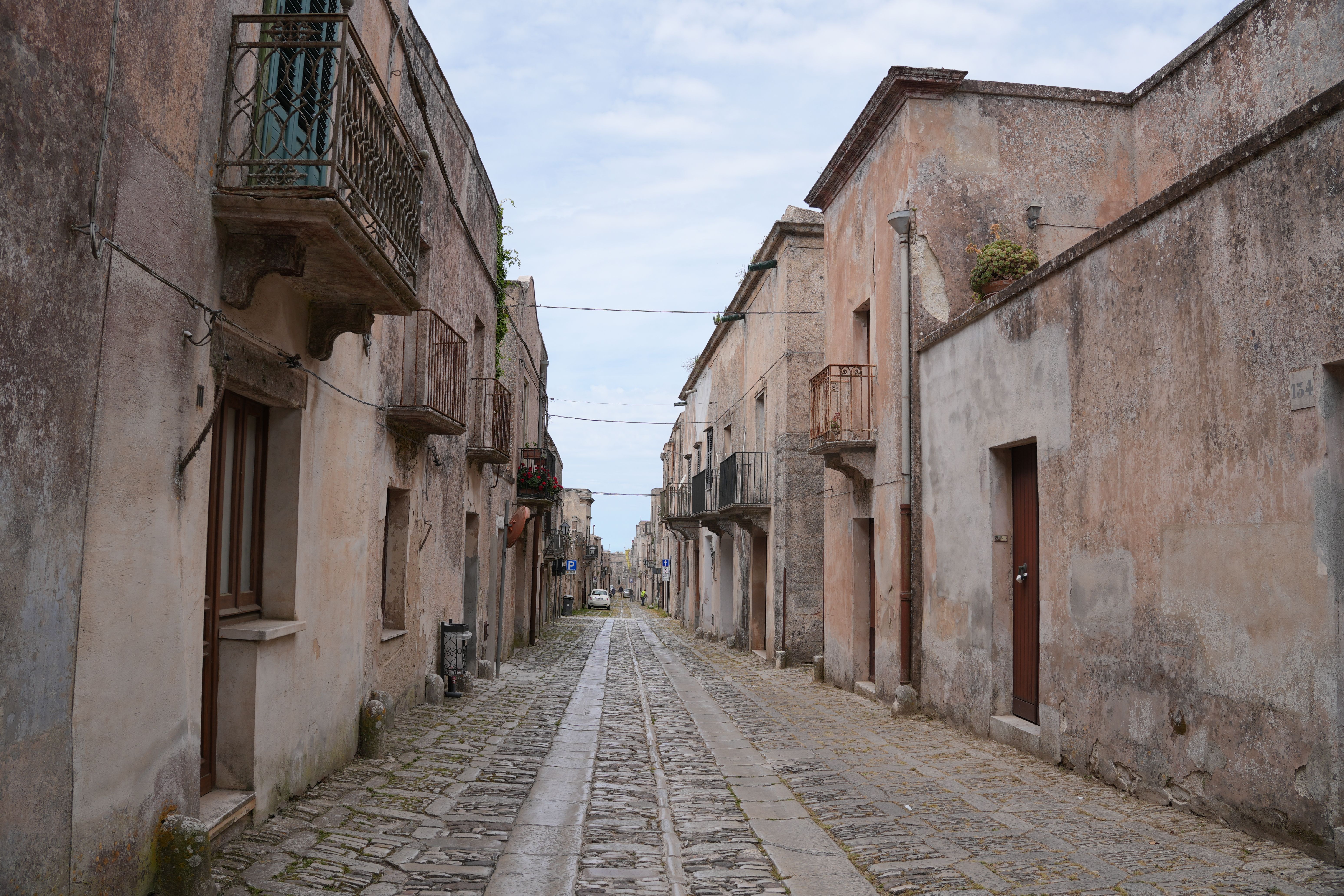 A tranquil view of a charming cobblestone street in Erice, Sicily, showcasing old architecture.