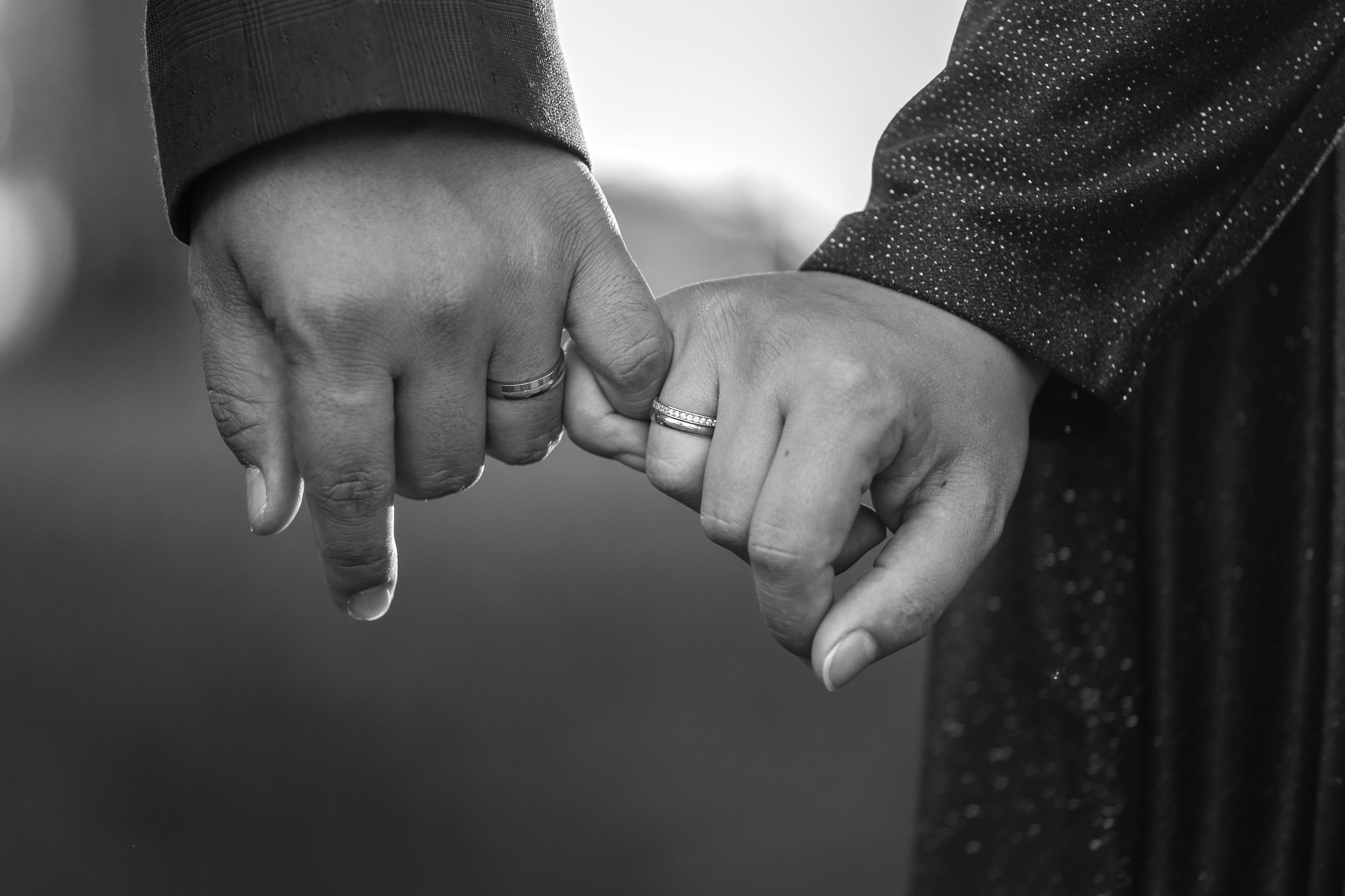 無料 手をつないで婚約指輪を見せ、献身と愛を象徴するカップルの白黒画像。 写真素材