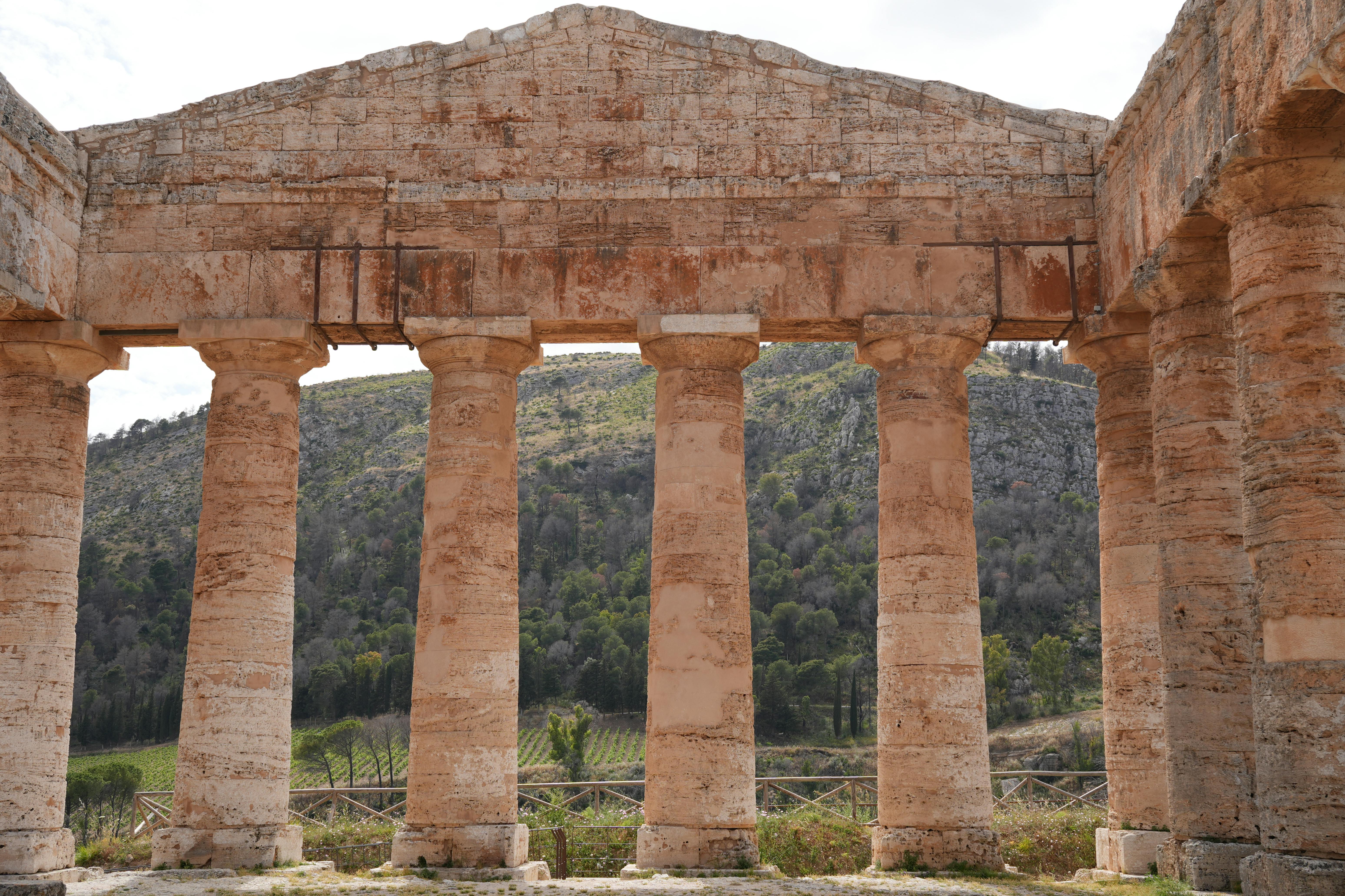 The weathered stone columns and archways of ancient temple ruins, partially overgrown with vines, bathed in the warm glow of sunset.