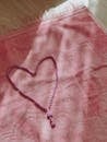 Pink prayer beads forming heart shape on cloth