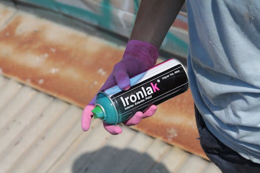 A person with pink gloves holds Ironlak spray paint, ready for graffiti art.