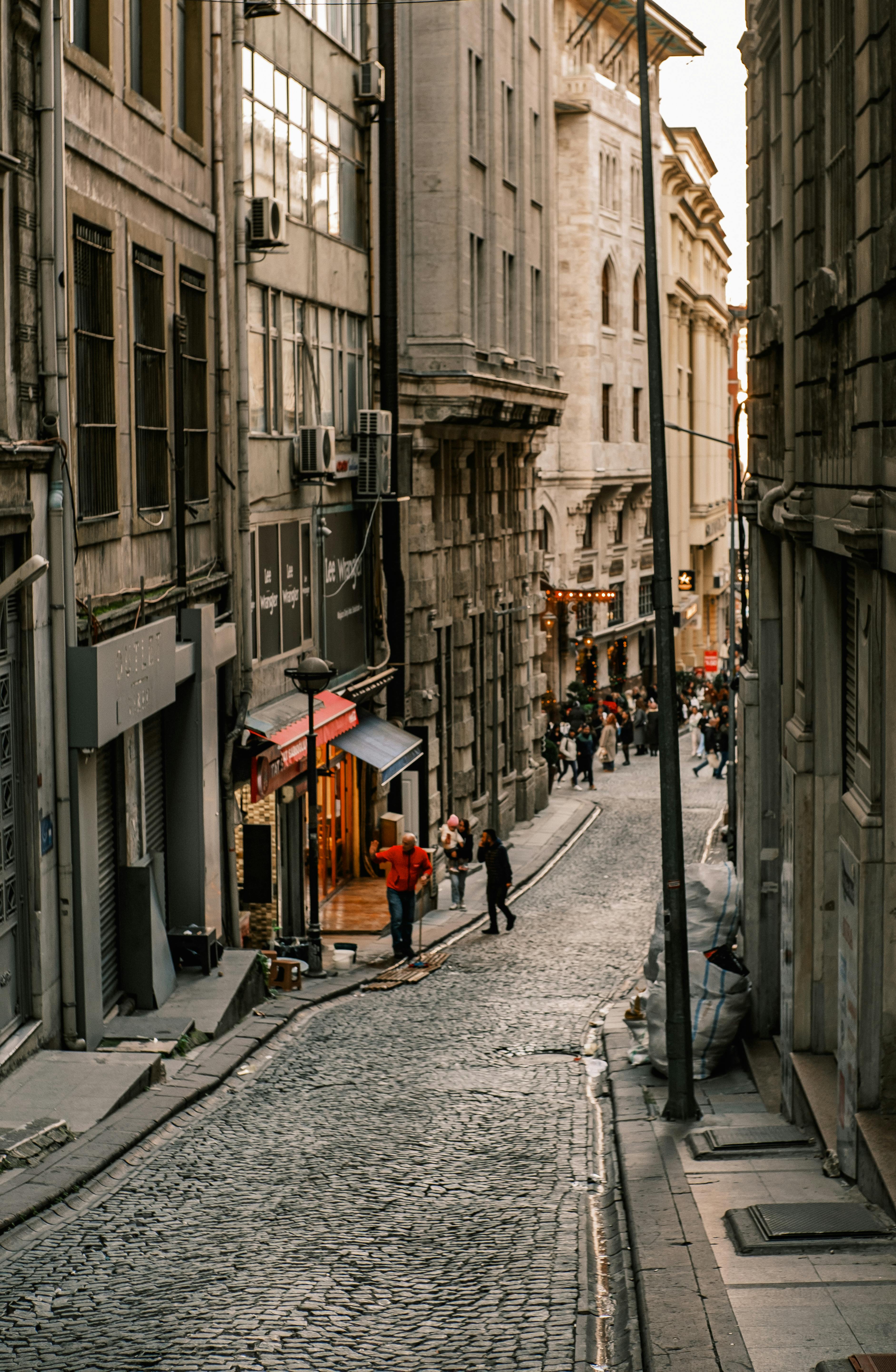 無料 歴史的なヨーロッパの都市の美しい石畳の道を、夕暮れ時に歩く人々。 写真素材