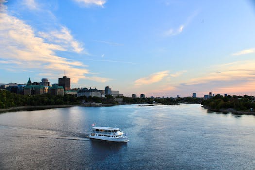一艘游船在明亮的天空下，以城市天际线为背景，航行在河流上