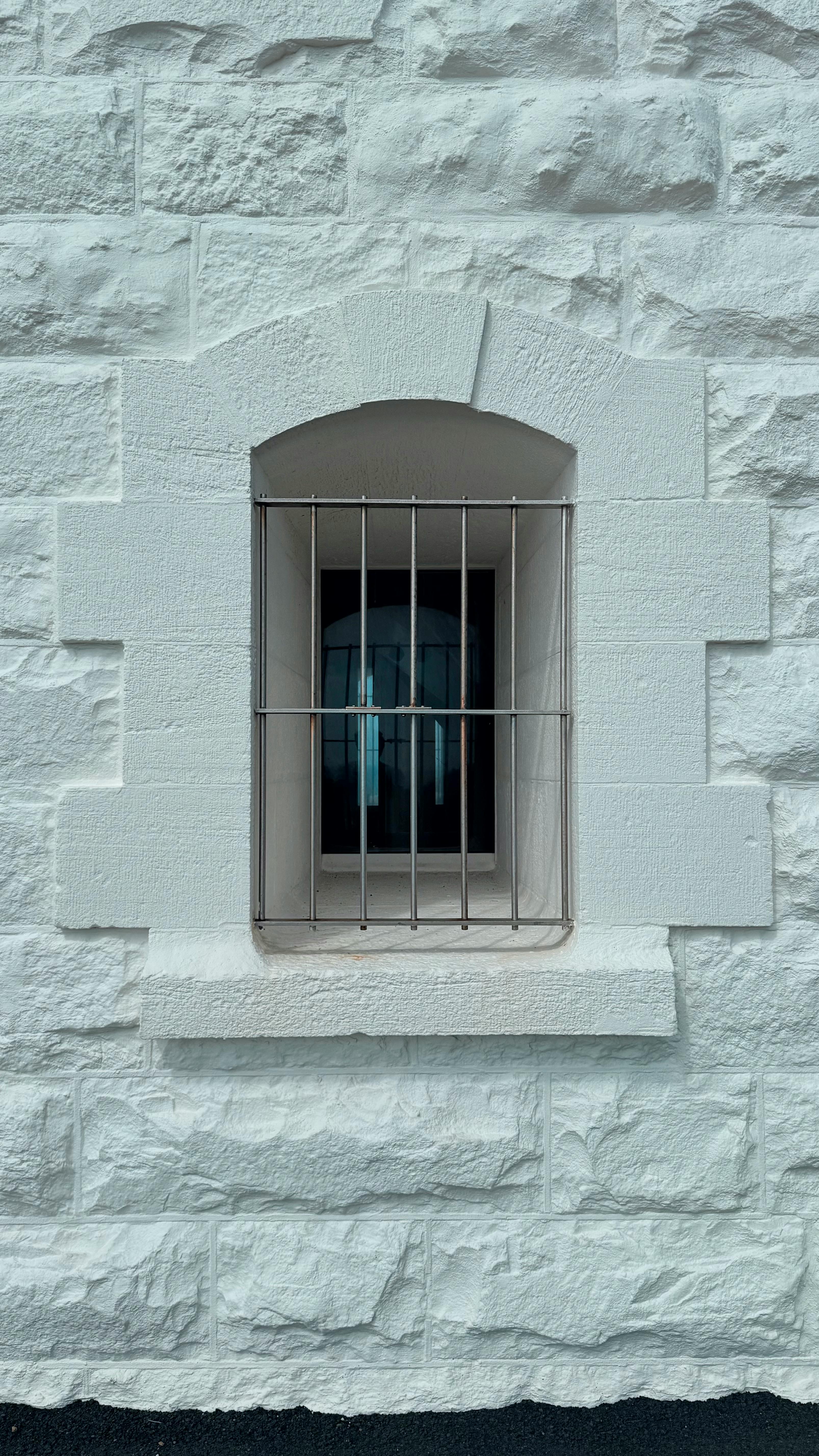 бесплатная Крупный план зарешеченного окна на белой каменной стене, демонстрирующий архитектурный дизайн и текстуру. Стоковое фото