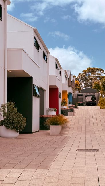 Photo by Sasha Vukovic on Pexels A vibrant row of colorful townhouses under a bright blue sky, symbolizing modern urban living.