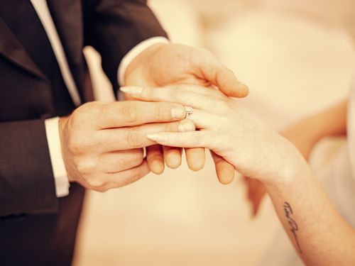 Free Close-up of a groom placing a diamond ring on the bride's finger during a wedding ceremony. Stock Photo