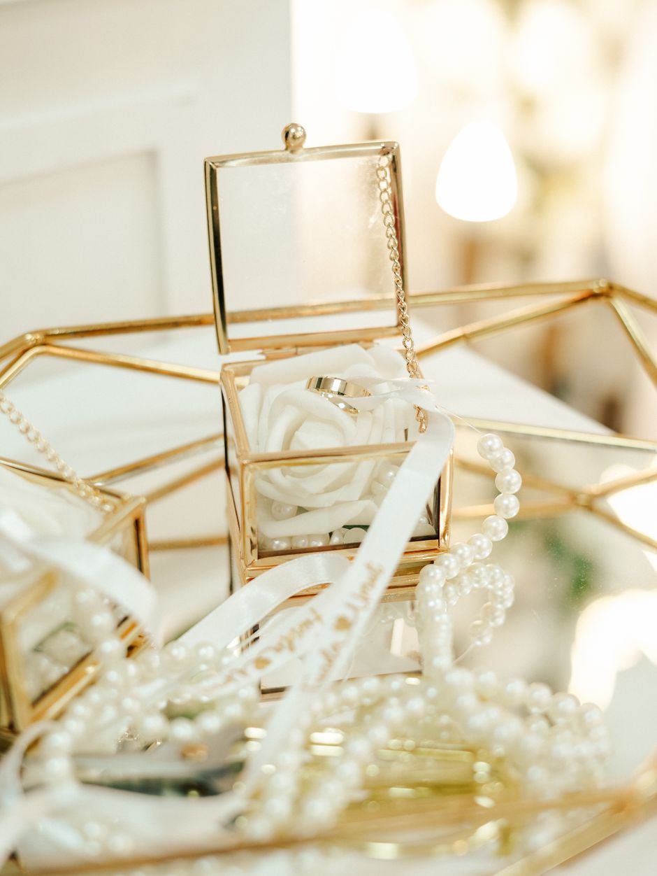 Pearls and wedding rings arranged around a glass jewelry box