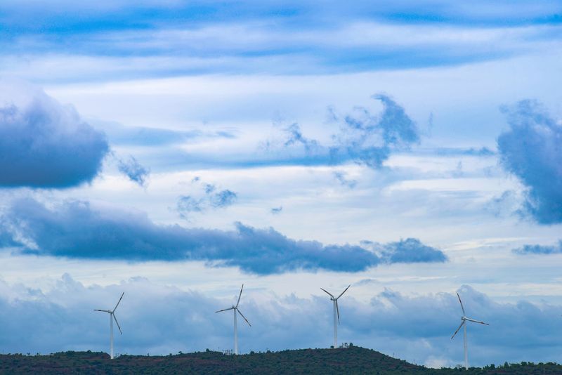 Wind turbines standing above a bank of cloud — photo by Visual Entity on Pexels