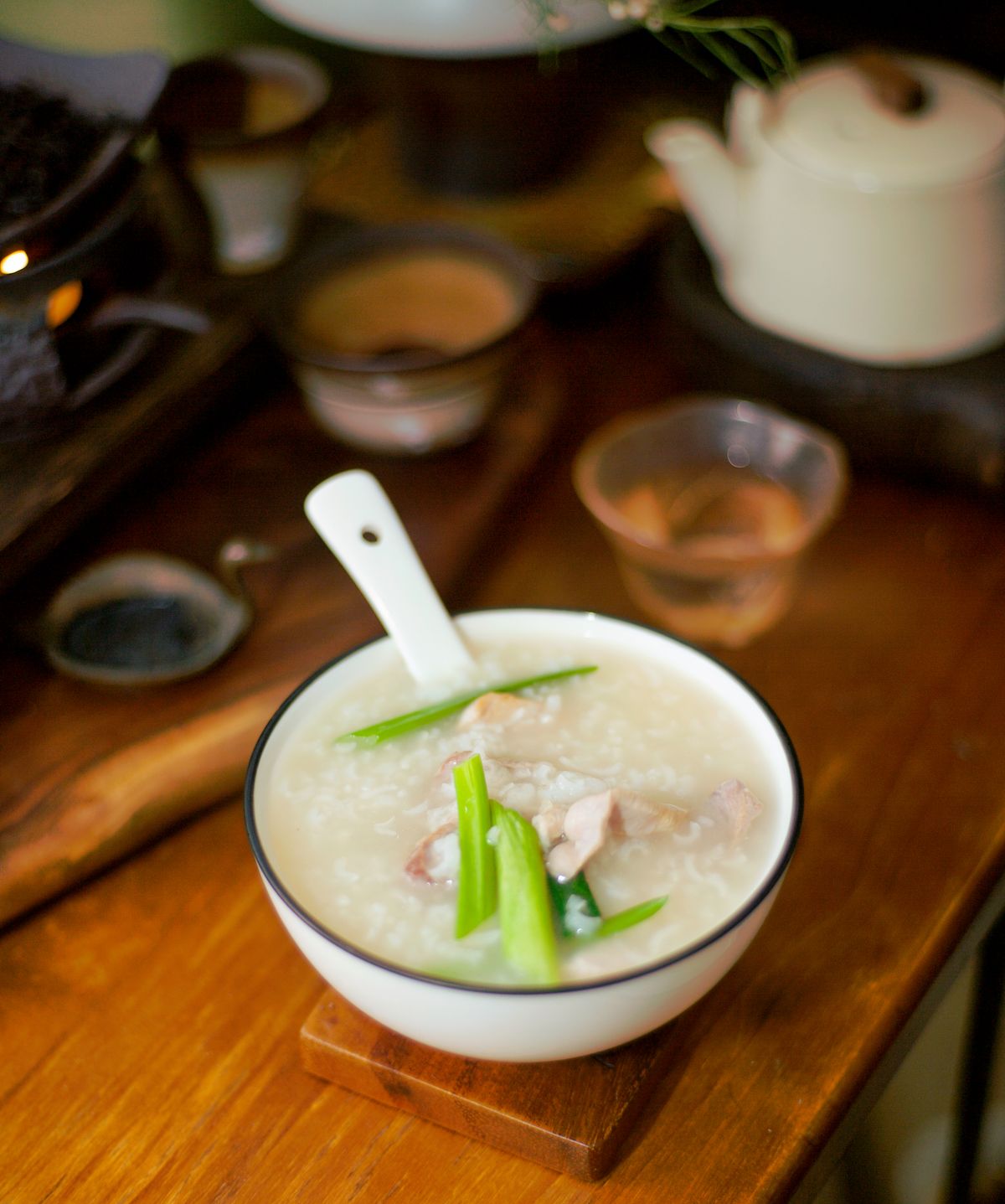 Thick white rice jok with chicken and spring onion in a white bowl