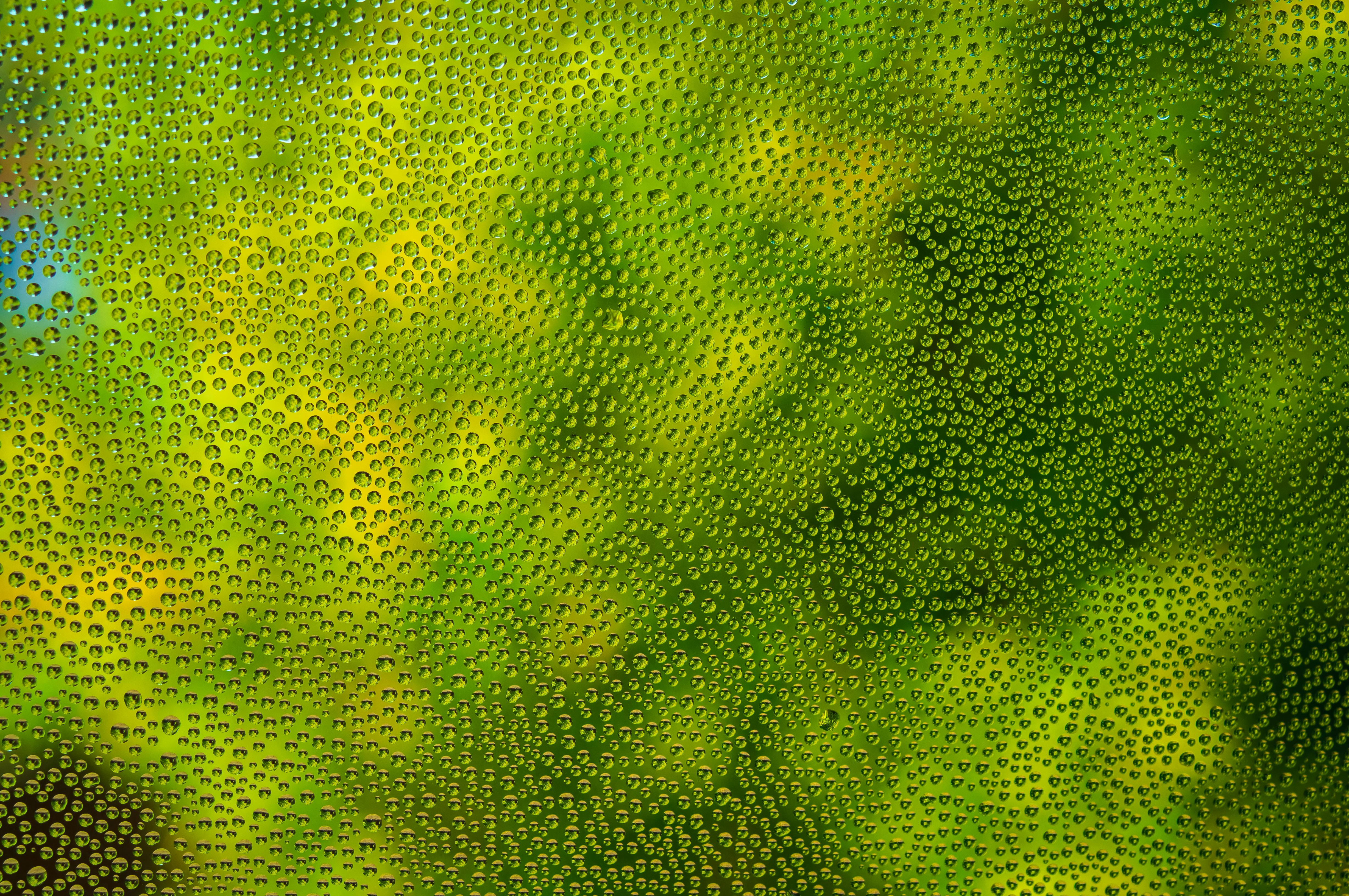 Free Close-up of dew drops on glass with a green abstract effect, creating a refreshing natural texture. Stock Photo