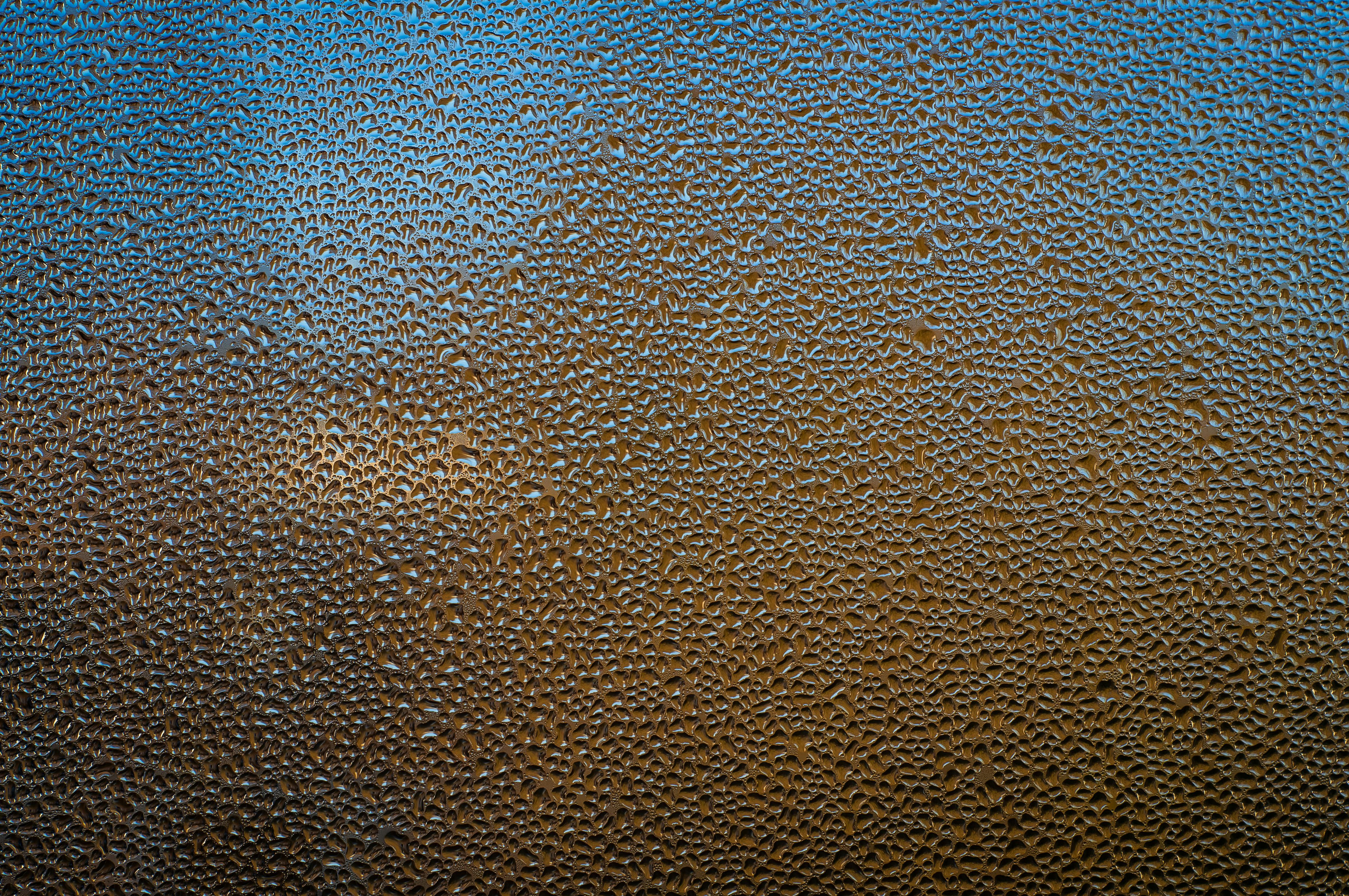 Free Artistic close-up of condensation forming tiny water droplets on a glass surface with vibrant colors. Stock Photo